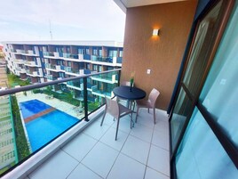 A balcony with a pool, a table, and chairs.
