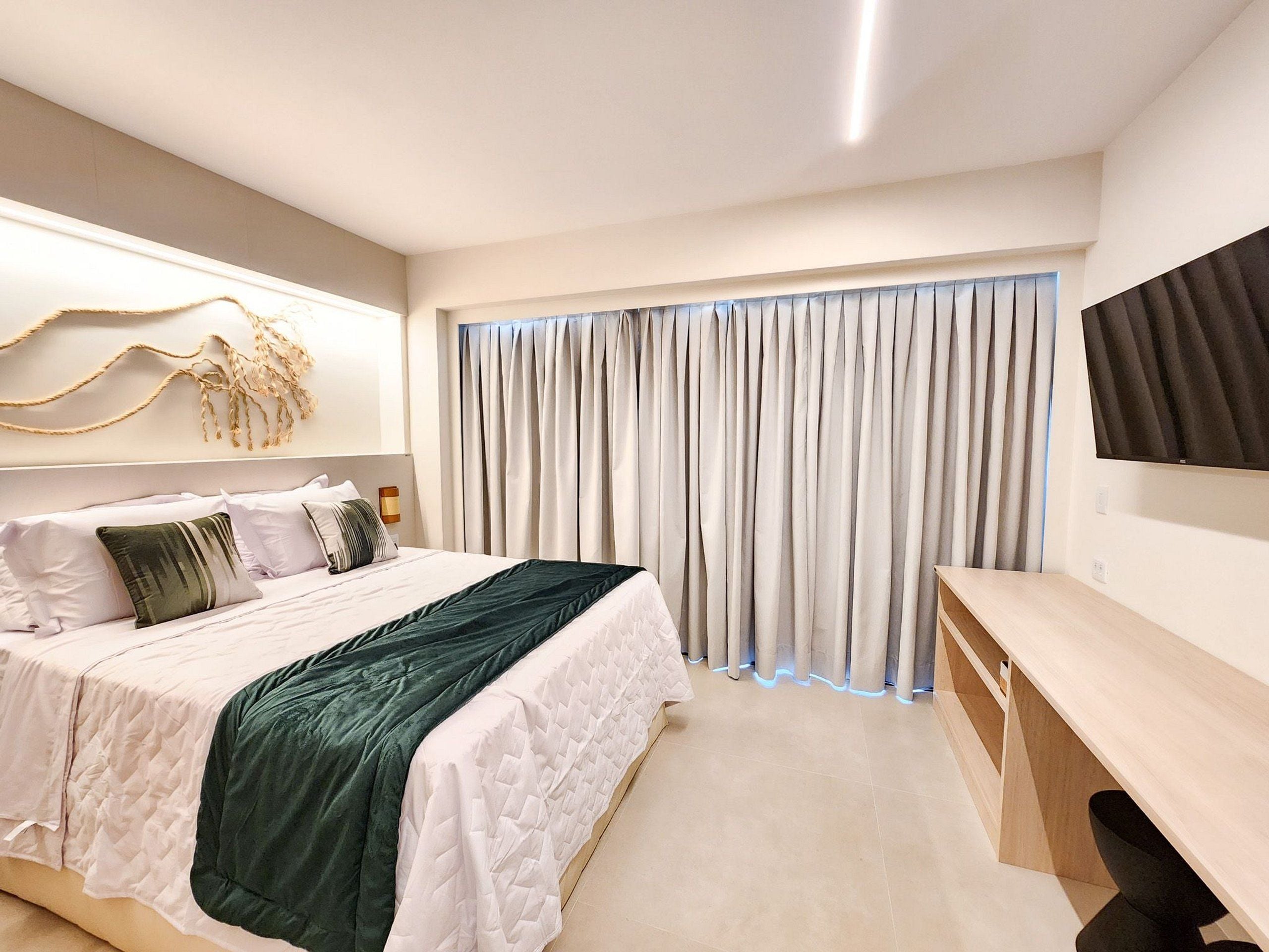 A modern bedroom with a bed, a desk, and a large window with curtains.