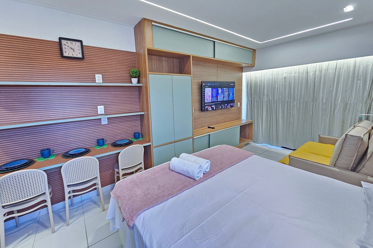 Une chambre d’hôtel moderne équipée d’un lit, d’une télévision, d’un bureau avec des chaises et d’une fenêtre avec des rideaux.