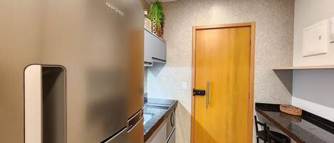 A kitchen with a stainless steel refrigerator, wooden door, and bar stools.