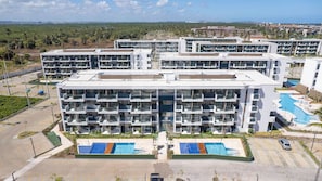 Un hotel de varios pisos con un atrio central, piscinas exteriores y un estacionamiento.