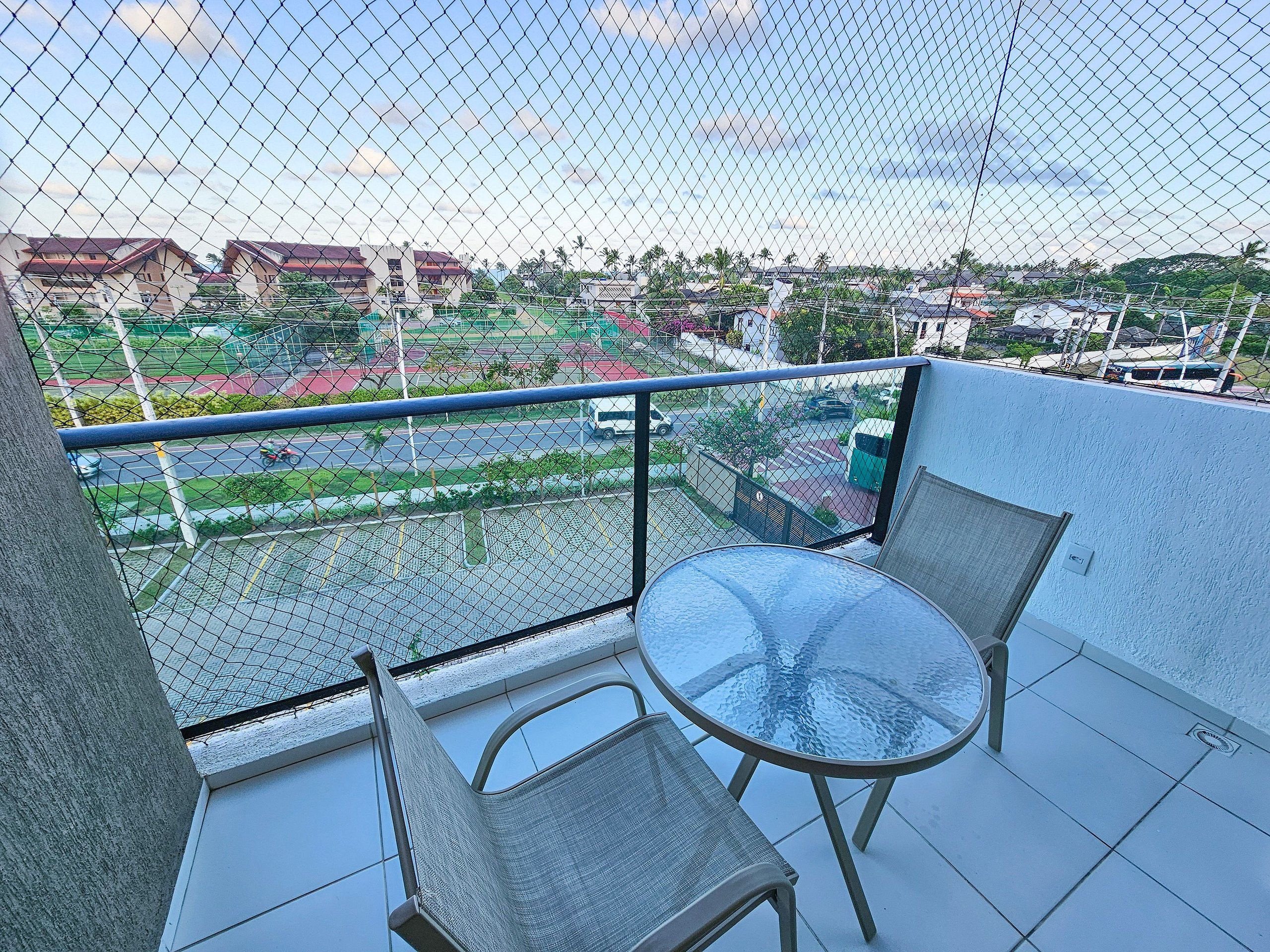 Un balcón con una mesa y dos sillas, con vista a una zona residencial con casas y vegetación.