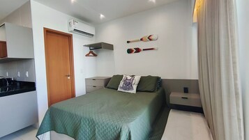 Un dormitorio con cama, almohada y auriculares, perchero y aire acondicionado de pared.