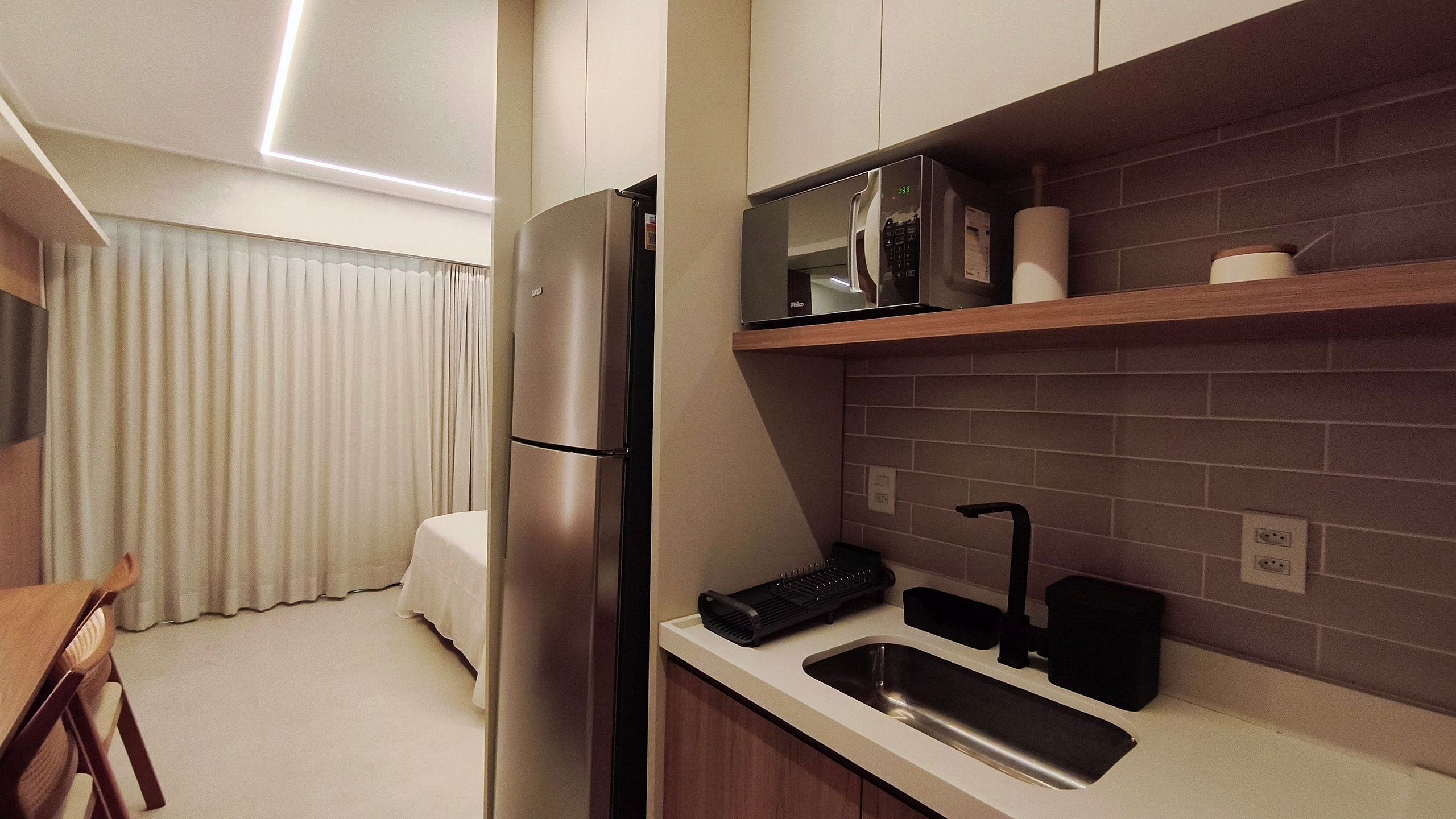 Una cocina moderna con refrigerador, microondas y lavamanos.