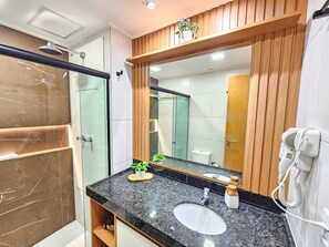A modern bathroom with a glass shower enclosure, a wooden vanity with a sink, and a large mirror. - Makia Beach Experience (Ipojuca)