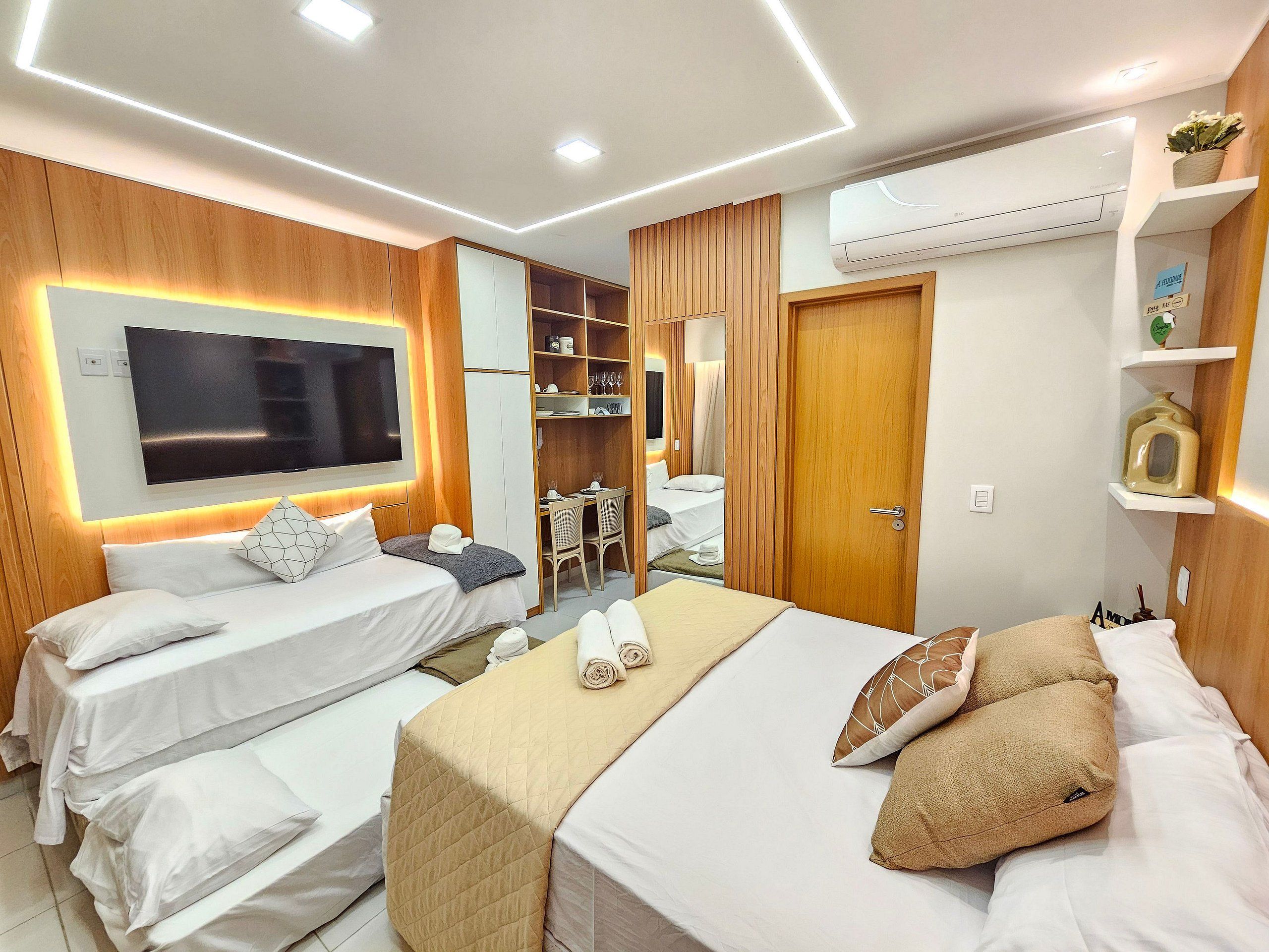Habitación de hotel con dos camas, televisión, armario y escritorio.