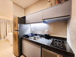 Una cocina moderna con horno empotrado, un lavamanos y una encimera con cocina por inducción negra.