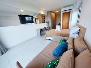 A hotel room with a bed, a sofa, a desk, and a TV. - Makia Beach Experience (Ipojuca)