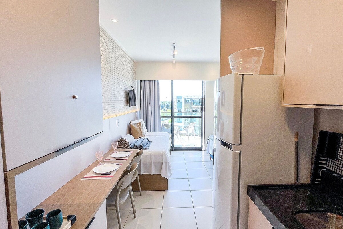 A modern kitchen with a dining area, a refrigerator, and a view of the outside.