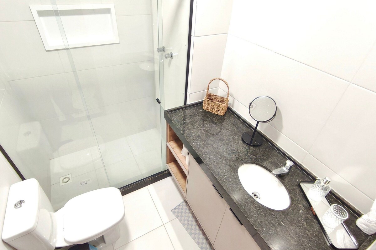 A bathroom with a glass shower enclosure, a sink with a mirror, and a toilet.
