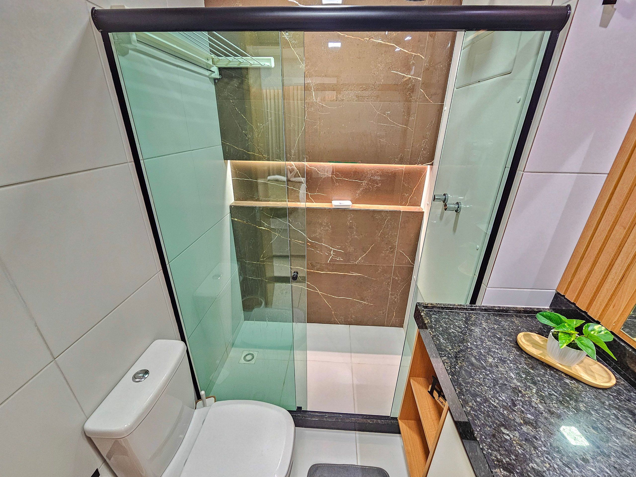 A modern bathroom with a glass-enclosed shower, a toilet, and a vanity with a sink and countertop.