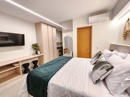 A modern bedroom with a bed, a TV, a wardrobe, and a desk.