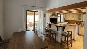 A spacious kitchen with wooden cabinets, a dining area with a large table and chairs, and a ceiling fan.