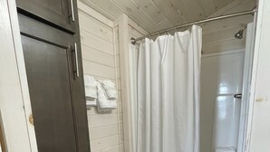 A bathroom with a toilet, a shower with a curtain, and a towel rack with towels.