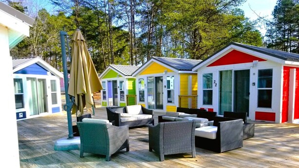 A row of colorful mobile homes with outdoor seating areas.