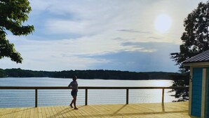 A wooden deck with a railing overlooking a lake.