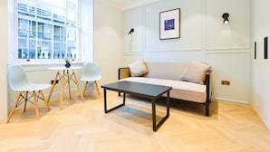 A modern living room with a sofa, a coffee table, and two white chairs. - Star Street Serviced Apartments by Concept Apartments (London)
