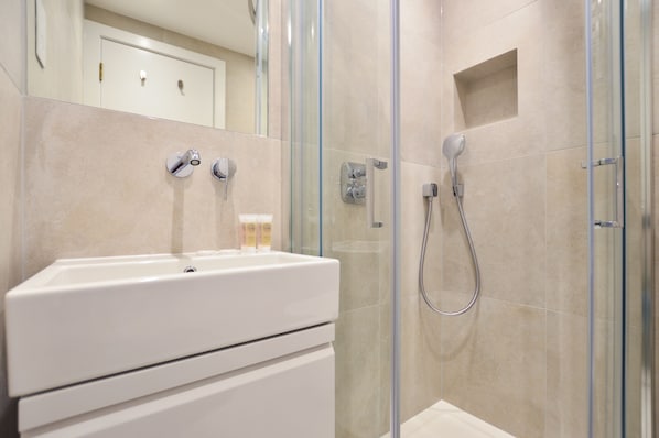 A modern bathroom with a glass-enclosed shower, a white sink, and a mirror above the sink.