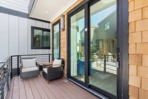 A balcony with wicker furniture and a sliding glass door. - Paradise at The Cove Riverwalk Villas (Wilmington)