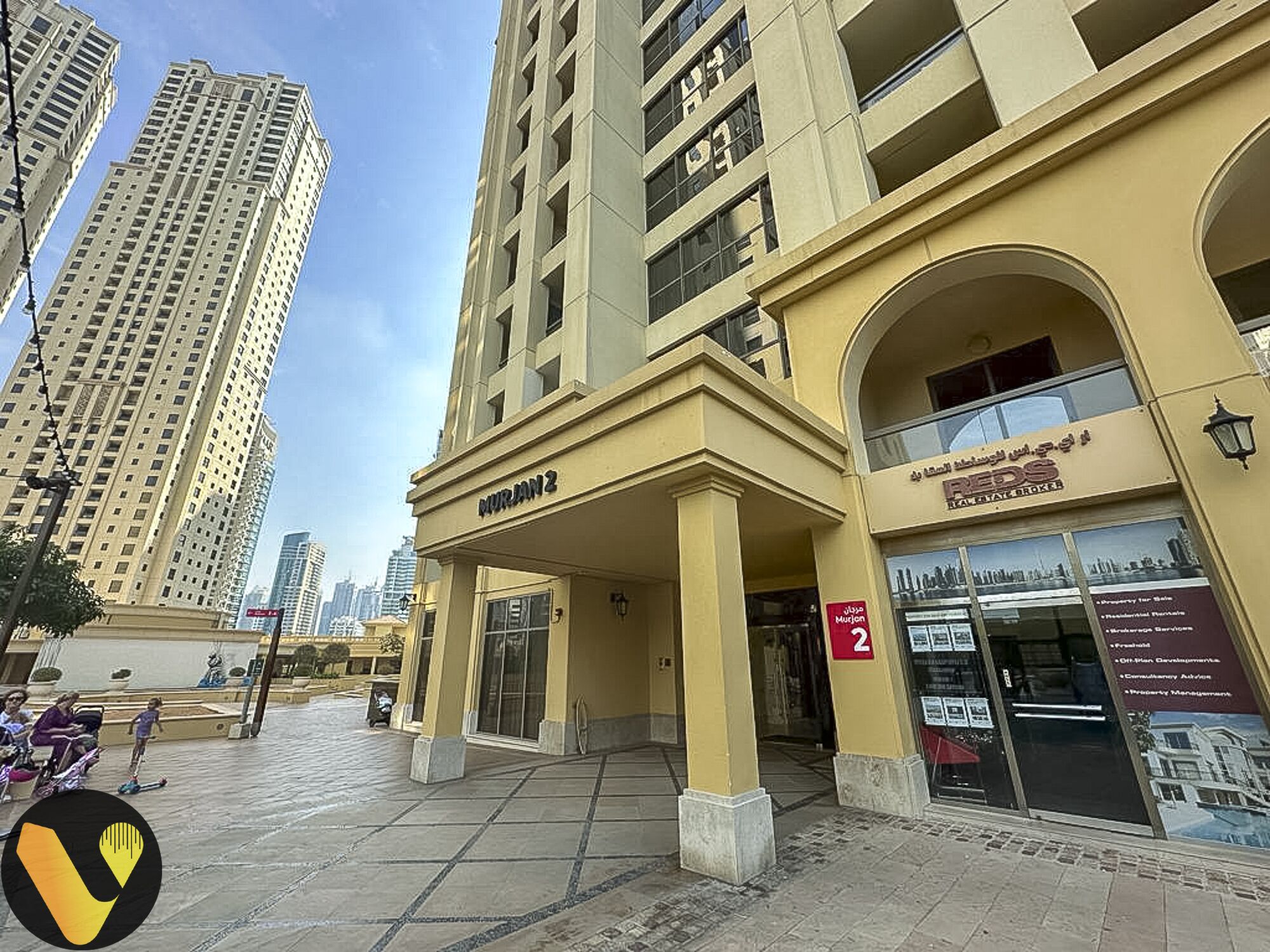 A building with a sign reading "MURJAN 2" and a sign for "REDS Real Estate".