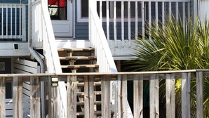 A two-story house with a front porch, a red umbrella, and a wooden fence. - Navarre Beach "Into the Mystic" Cozy & Unique Townhome (Navarre)