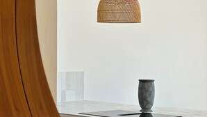 A kitchen with a wooden cabinet, a white tiled backsplash, and a hanging woven light fixture.