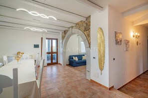 A spacious room with a dining area, a blue sofa, and a stone wall.