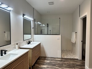 Een moderne badkamer met twee wastafels, een grote spiegel en een douchegedeelte.