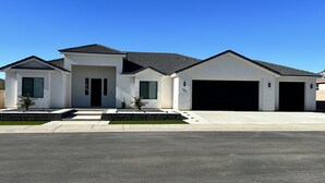 A modern two-story house with a garage, a well-maintained lawn, and a clear blue sky. - Modern Mesquite New Home perfect for golfers and families alike. (Mesquite)
