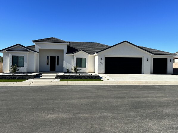 Een modern huis met twee verdiepingen, een garage, een verzorgd gazon en een helderblauwe lucht.