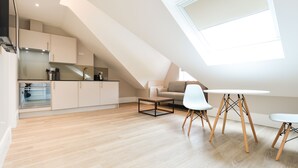 A modern loft-style apartment with a kitchen, dining area, and a large skylight. - Woodview Serviced Apartments by Concept Apartments (London)