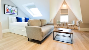 A modern loft bedroom with a bed, a sofa, and a dining table. - Woodview Serviced Apartments by Concept Apartments (London)
