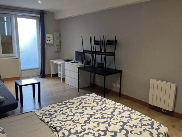 Une chambre à coucher avec un lit, un bureau, une chaise et un radiateur.