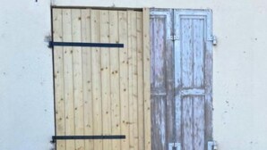 Un bâtiment doté d’une porte et d’une fenêtre en bois, d’un seuil en béton et d’un petit auvent.