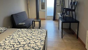Une chambre d’hôtel comprenant un lit, un canapé, une petite table, un bureau avec des chaises et une vue sur l’extérieur.