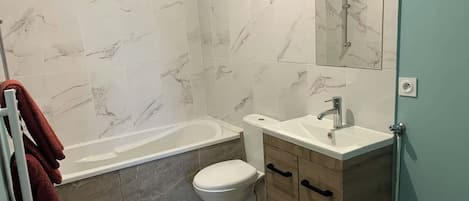 A bathroom with a bathtub, toilet, and vanity.