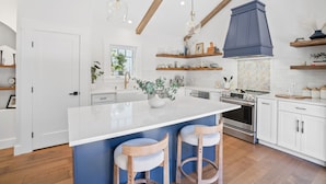 A modern kitchen with a large island, wooden bar stools, a built-in oven, and a blue range hood. - Charming New Casita Lower Riviera, Quiet, AC, 6 blocks to State St, Pet-Friendly (Santa Barbara)