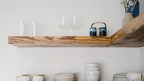 A kitchen with white tiles, wooden shelves, and a coffee maker. - Charming New Casita Lower Riviera, Quiet, AC, 6 blocks to State St, Pet-Friendly (Santa Barbara)