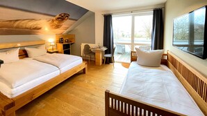 Une chambre d’hôtel avec deux lits, un bureau, une chaise et une fenêtre avec des rideaux.