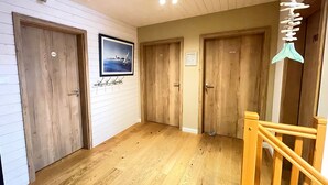 Un couloir avec des portes en bois, un tableau encadré au mur et une rambarde en bois.