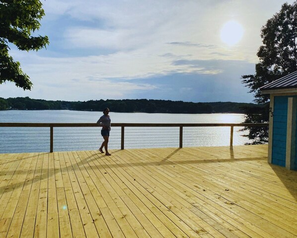 A wooden deck with a railing overlooking a lake.