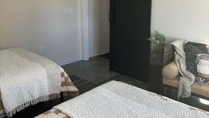 A modern bedroom with a bed, a black sliding door, a ceiling fan, and a small plant on a side table.