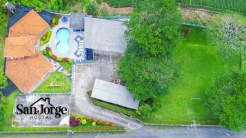 Um imóvel residencial com piscina, vários telhados e um gramado bem cuidado.