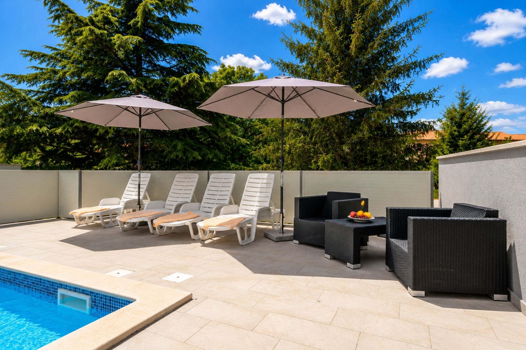 A poolside area with lounge chairs, umbrellas, and wicker furniture.