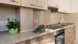 Une cuisine moderne avec des meubles de couleur claire, un évier en acier inoxydable et un four encastré.