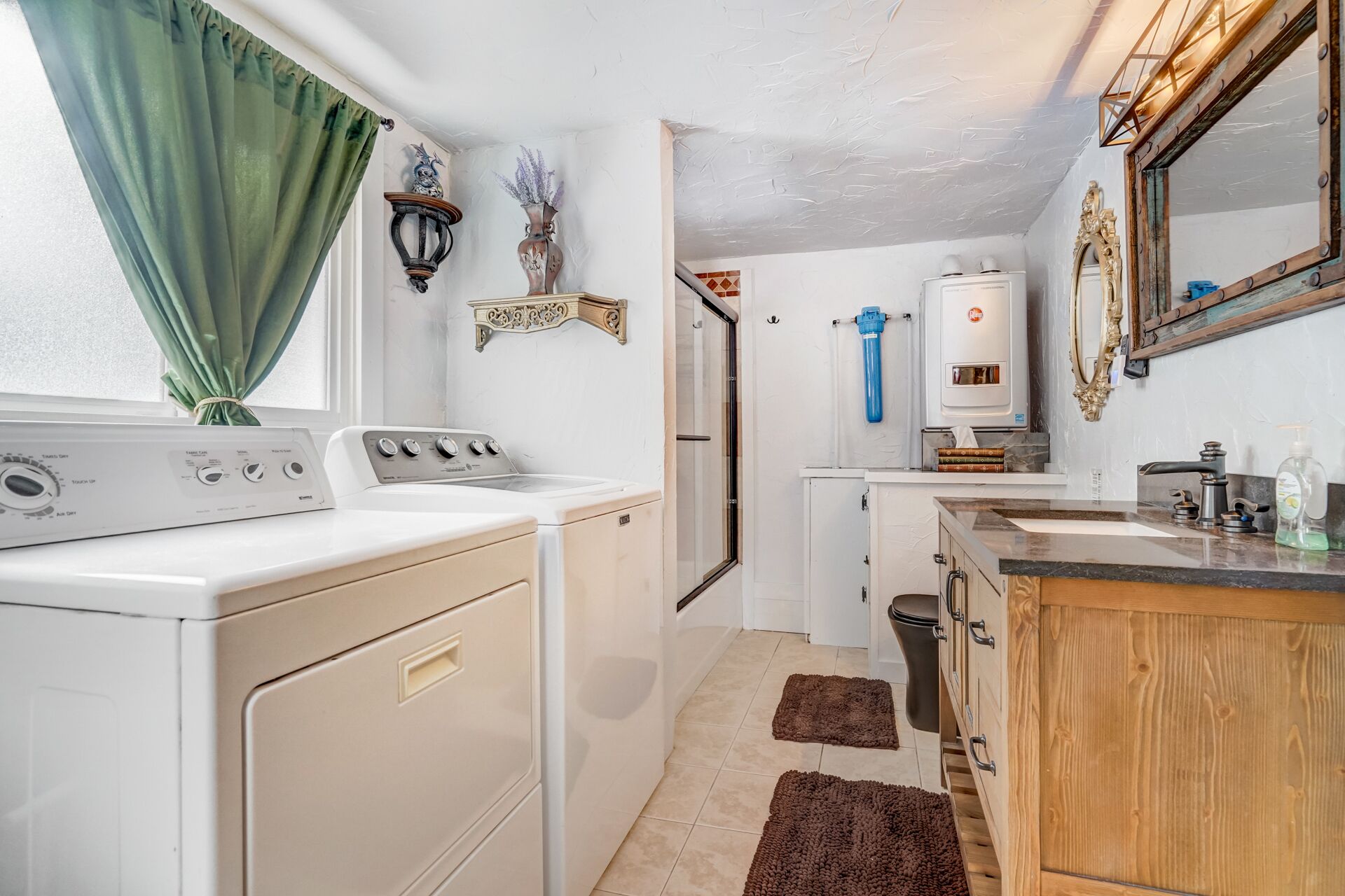A compact kitchen with a washing machine, a sink, and a mirror.