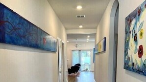 A hallway with wooden flooring, white walls, and artwork.