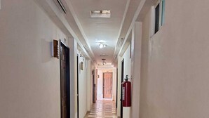 A long, narrow hallway with checkered flooring, doors on both sides, and a fire extinguisher on the right. - Hotel San Rafael Poza Rica (Poza Rica)