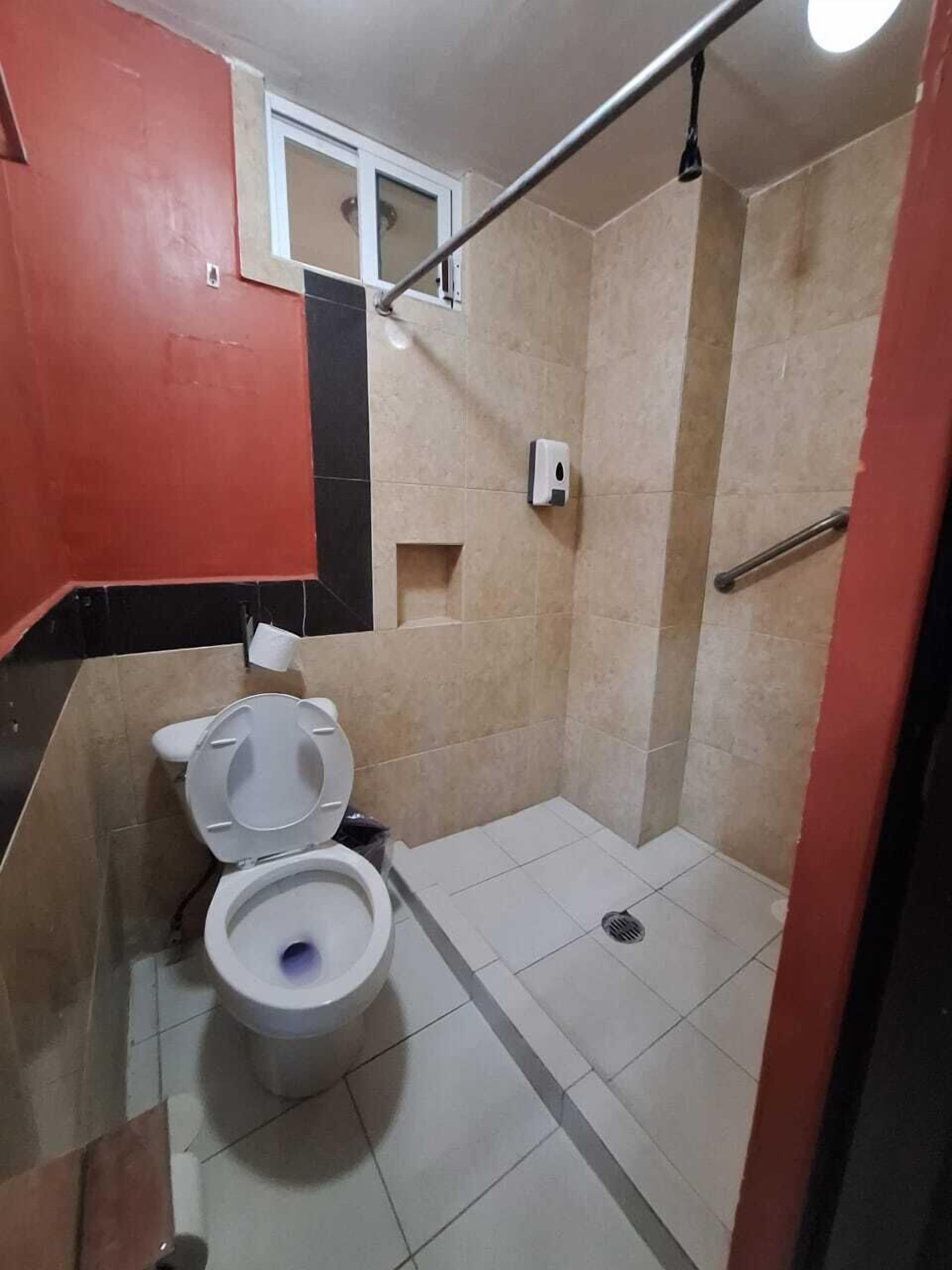 Ein kleines Badezimmer mit Toilette, Duschbereich und einem Handtrockner.