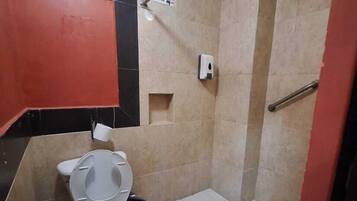 Ein kleines Badezimmer mit Toilette, Duschbereich und einem Handtrockner.